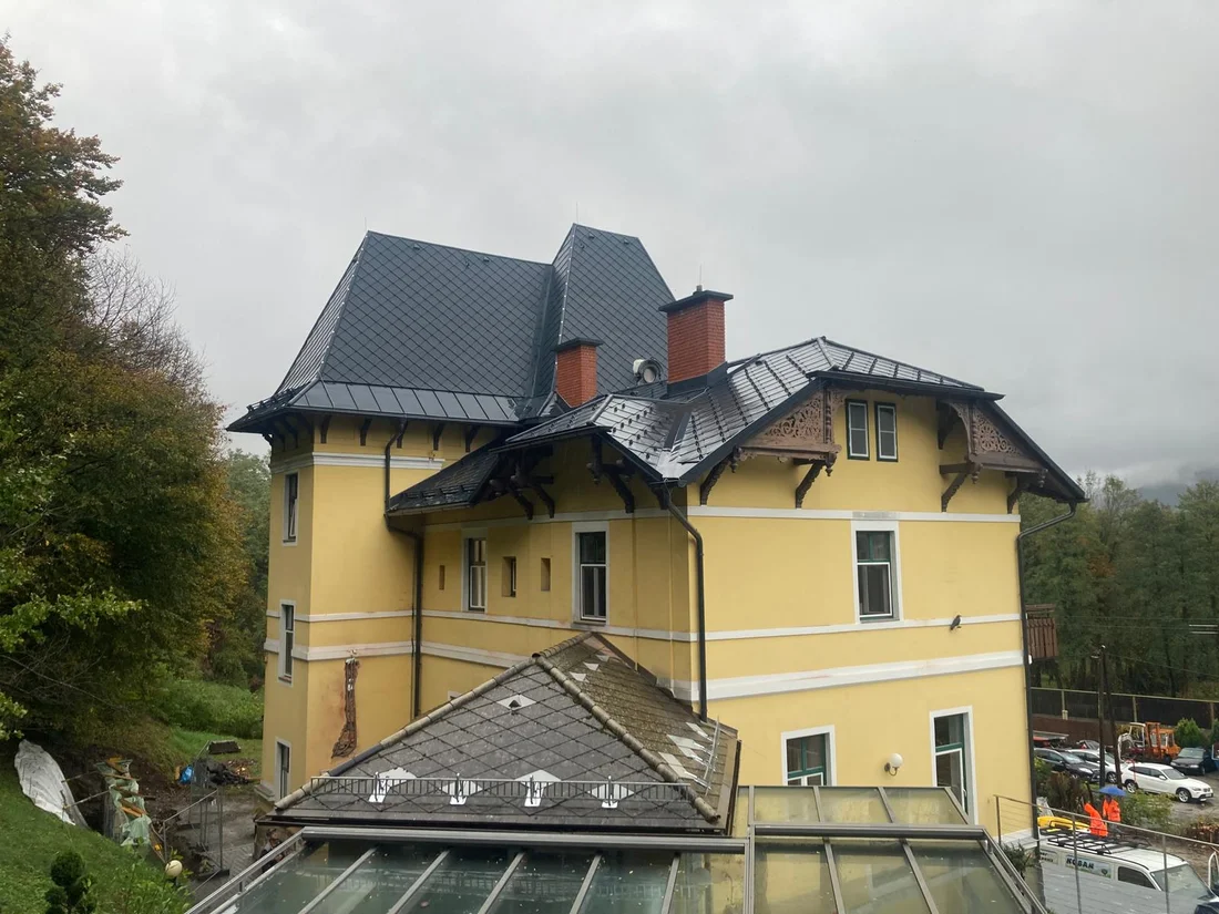 Seitenansicht der Villa mit Rautendach und Kaminen – Rautendach mit Zierdetails