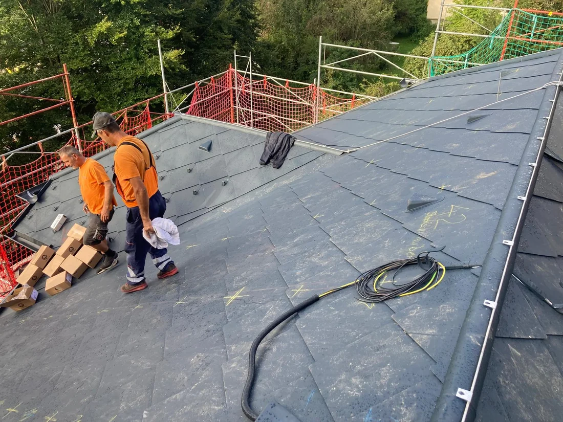 Handwerkliche Arbeiten auf der eingerüsteten Dachfläche – Rautendach mit Zierdetails
