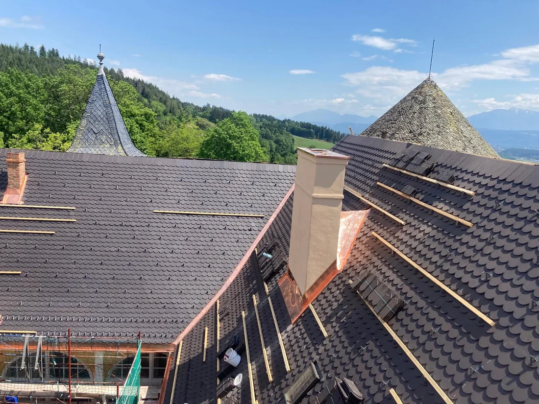 Dunkle Dachflächen im Innenhof von Schloss Tentschach mit Kaminen und Kehlen