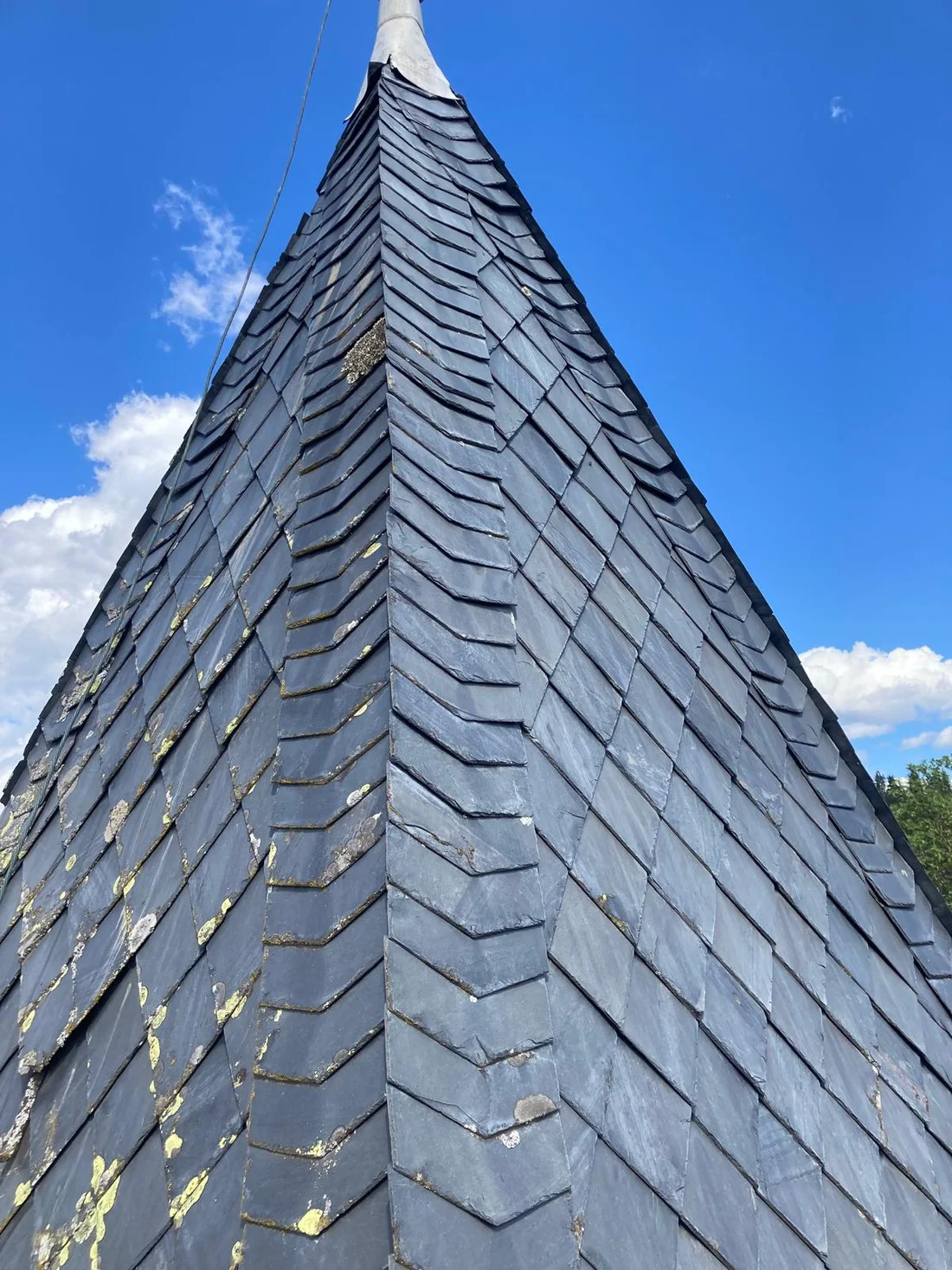 Schmale eingedeckte Dachspitze am Schloss Tentschach vor blauem Himmel